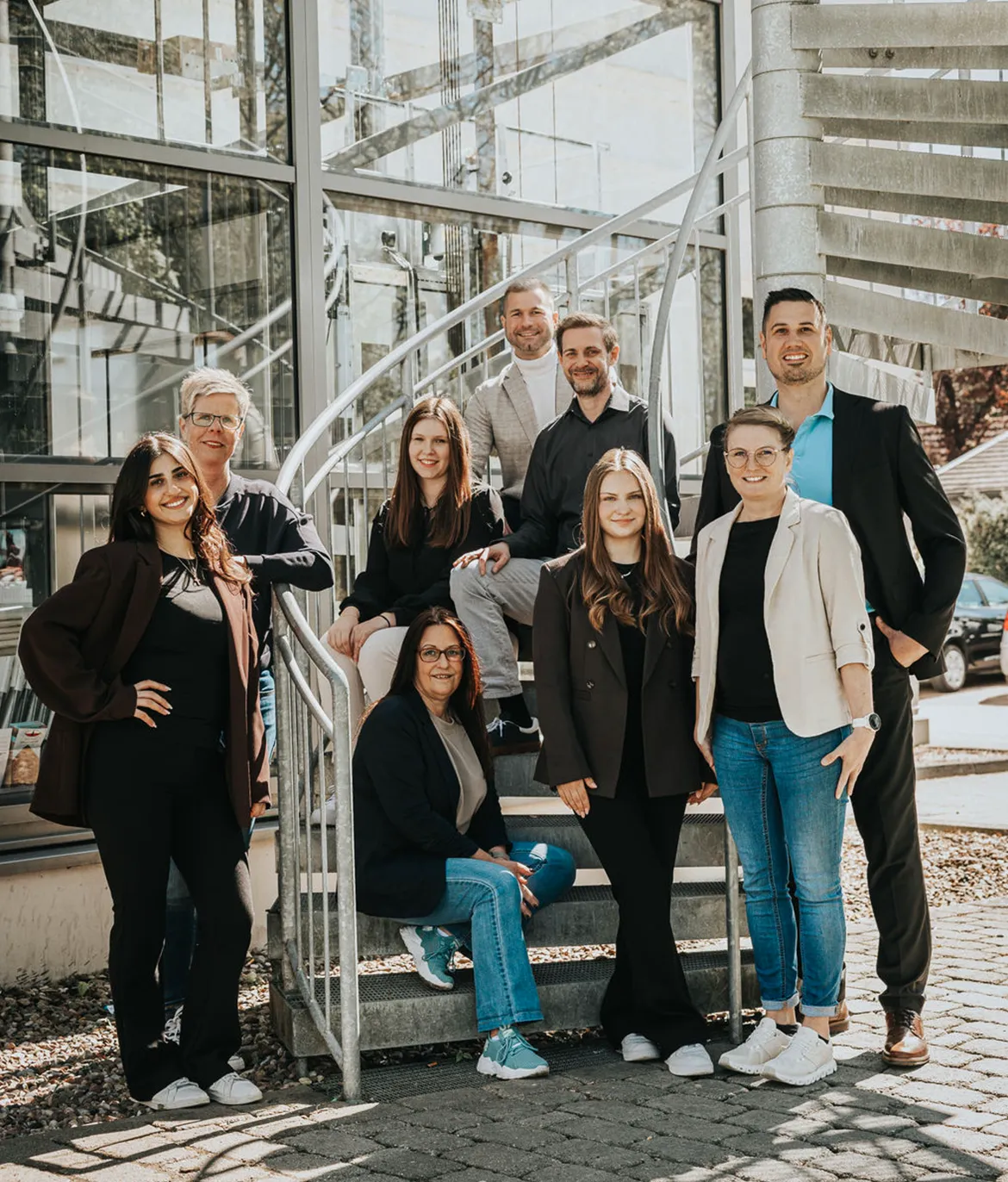 Team von Meyer & Team auf der Treppe vor dem Firmengebäude